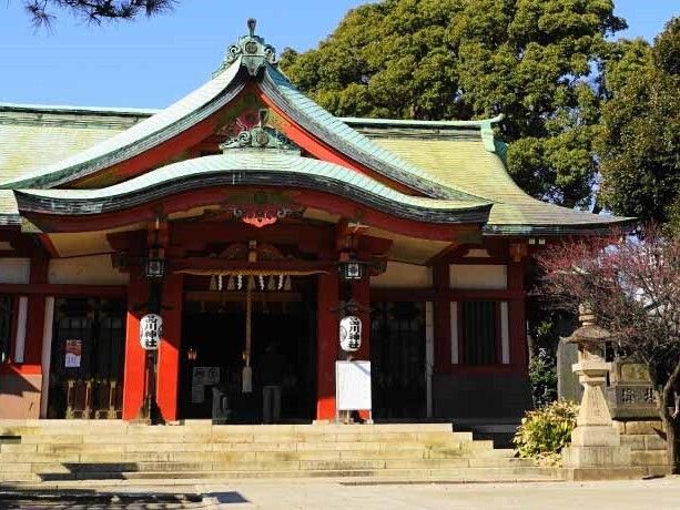 きれいに掃除がされた境内。歴史を感じられる薄い緑の屋根に朱色の柱。周りには草木が植えられている。