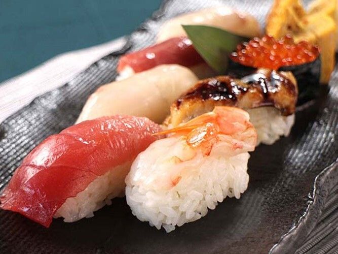 黒い陶器の器に盛られた握り寿司。マグロや卵、イクラ、ウナギ、貝類など、様々なネタが乗っている。