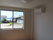 エアコンが付いたシンプルな部屋には大きな窓があり、カーテンはついていない。