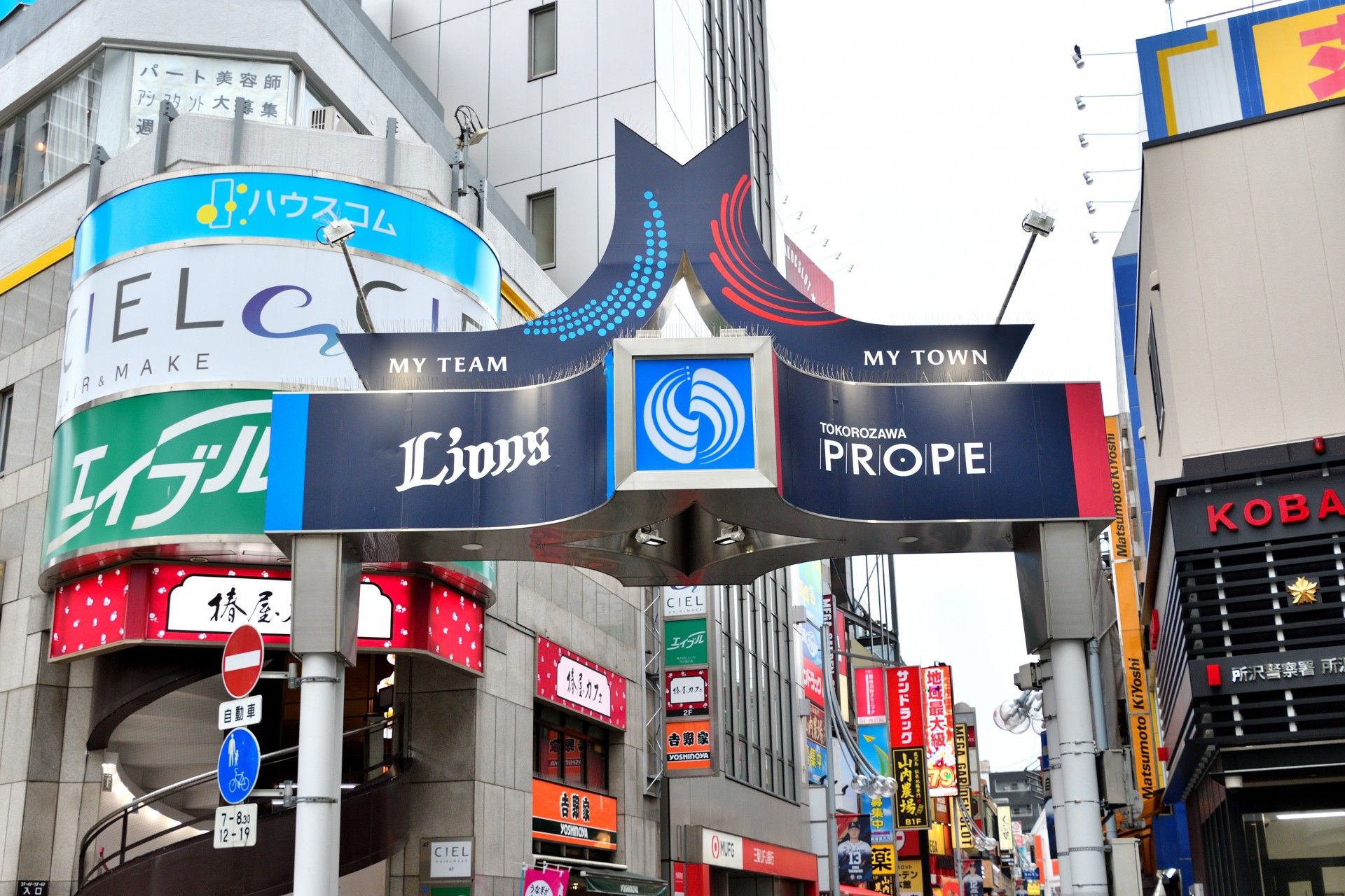 背の高いビルと交番の間に、商店街が続いている。たくさんのお店が立ち並んでおり、人通りが多い賑やかな通りである。
