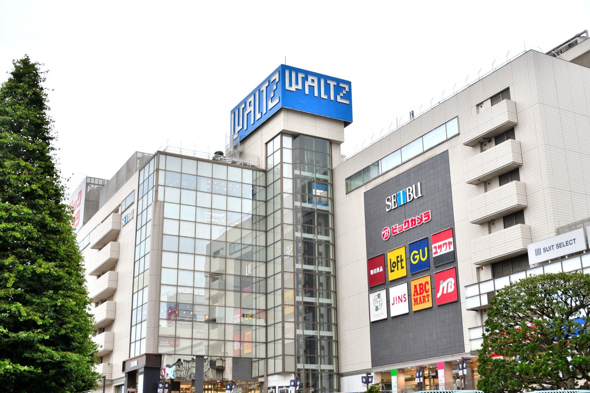 白とブルーのコンビニエンスストアの看板である。日用品や食料品、雑誌などが手軽に手に入り、便利である。