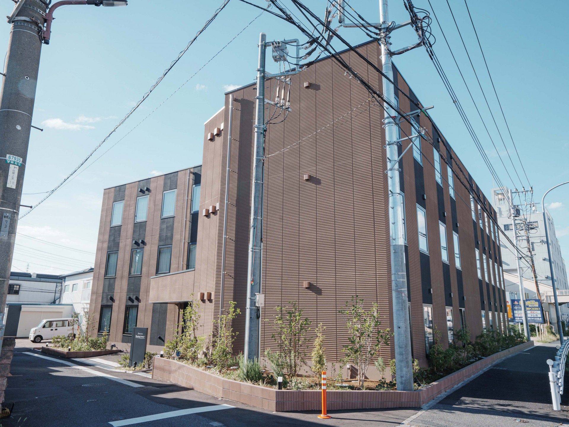 ブラウン系の3階建ての建物の周りには草木も植えられ、日当たりのいい場所に建っている。