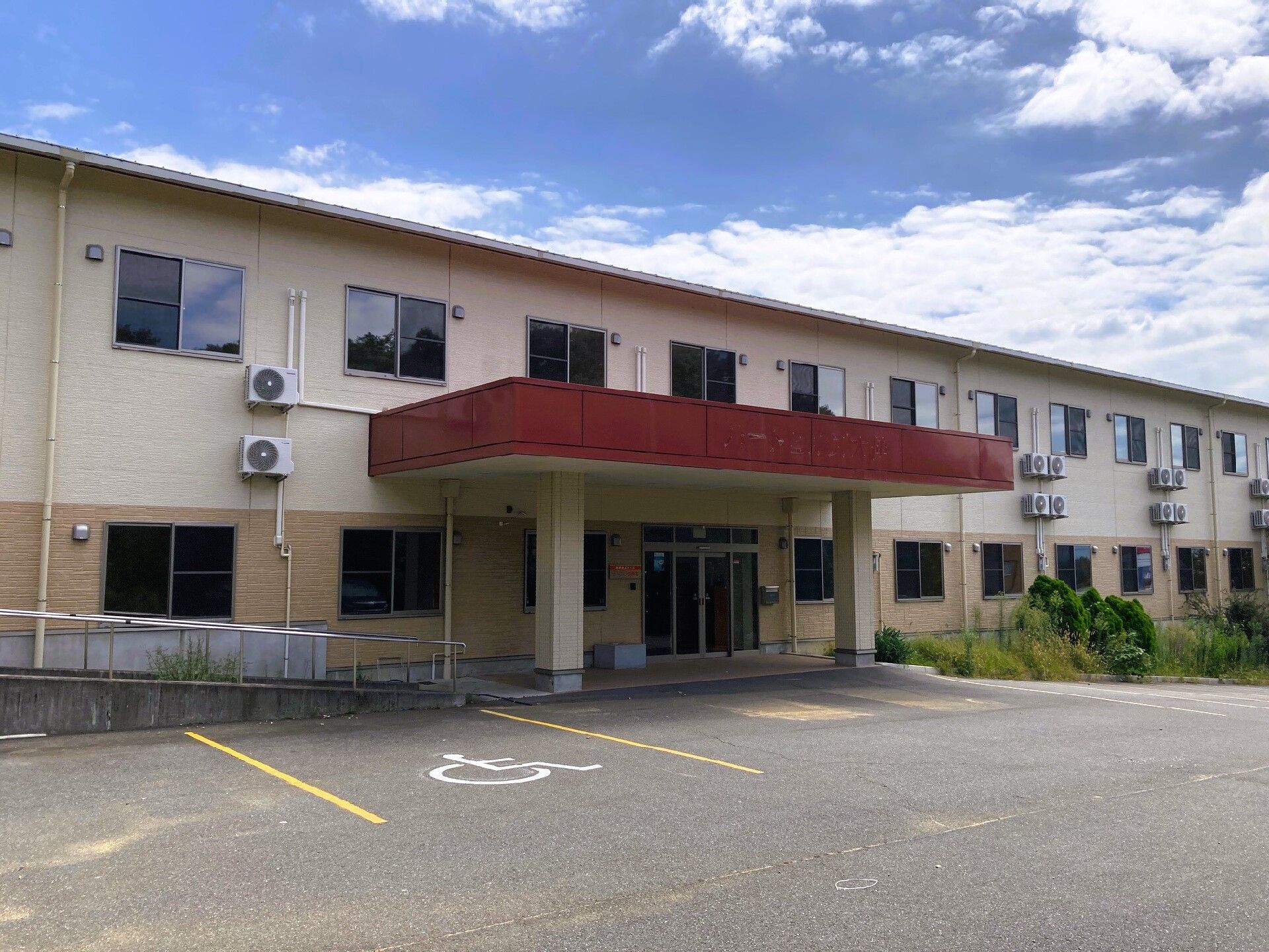 広い駐車場が付いた２階建ての建物は日当たり良好で横に長く、玄関には自動ドアが設置されている。