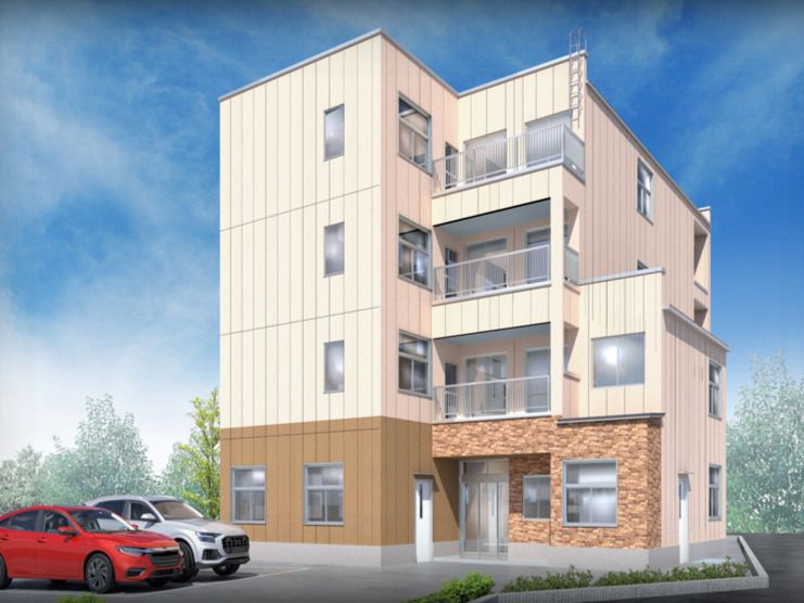 日当たりのいい場所に建っている4階建ての建物は白とブラウンで建物の前には駐車場もある。