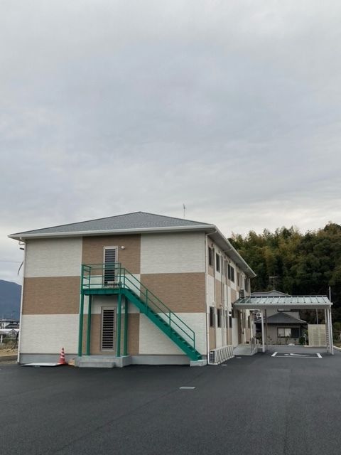 眼鏡をかけた高齢男性が福祉車両から降りようとしているところを手伝っているエプロンを付けた男性スタッフ。