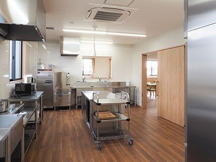 ステンレス製の調理器具がそろった厨房には窓があり、右側のドアの外には共有スペースがある。