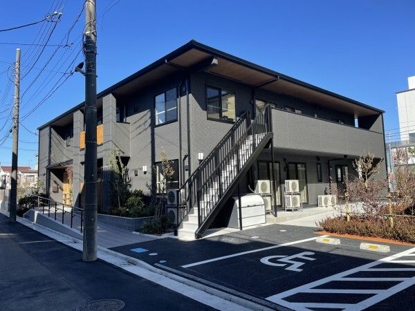 屋外階段が設置された２階建ての建物の外壁にはホーム名が書かれた看板があり、敷地内には駐車場もある。