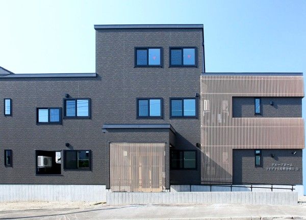 グレー基調の壁に木製のルーバーを組み合わせたモダンな外観。
