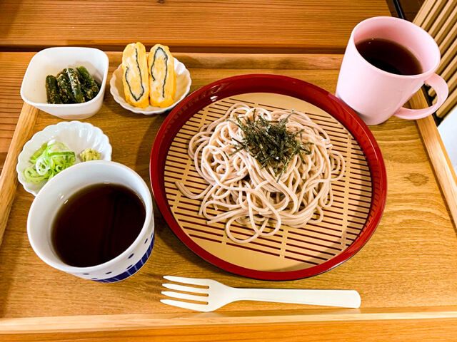 ざるそばをメインにつけ汁や珈琲、薬味、海苔入りの卵焼き、煮物などが添えられている。