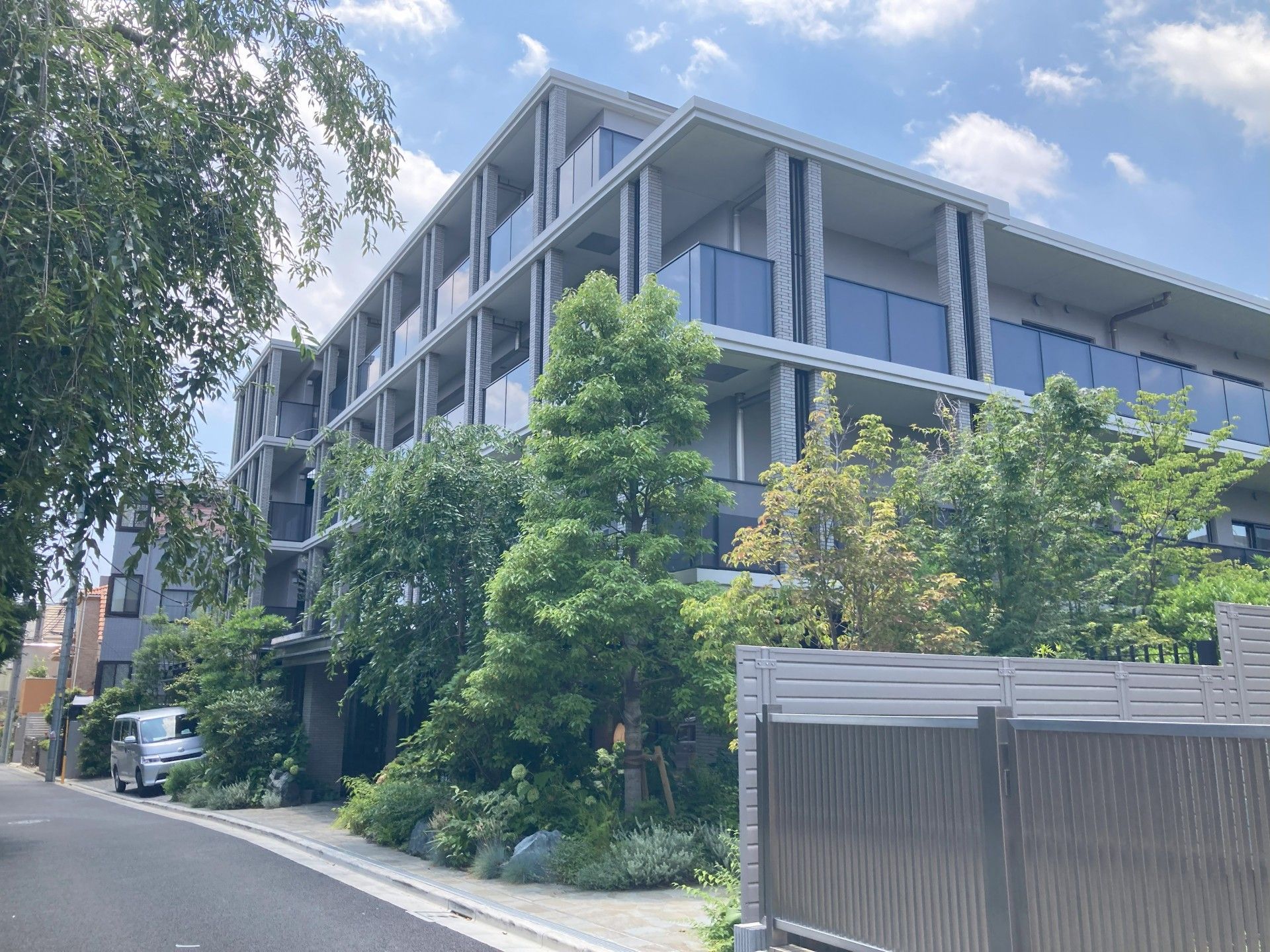 草木が植えられている敷地内には4階建ての建物があり、日当たり良好。各フロアにベランダもある。
