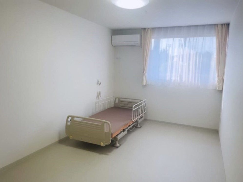 エアコンが付いた部屋には介護ベッドが置かれている。大きな窓もあり、明るい雰囲気。