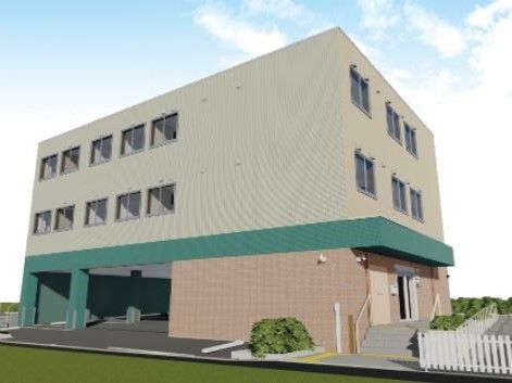 ベージュとグリーンの3階建ての建物の1階部分には駐車場もあり、周りには草木が植えられ、手摺付きの階段が玄関にある。