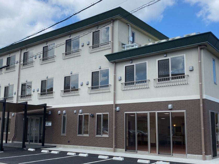日当たりのいい場所に建っている3階建ての建物は白とブラウンで玄関先には車寄せが付いている。