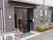 スライド式のドアが設置されたエントランスにはマットが敷かれ、建物の周りには木が植えられている。