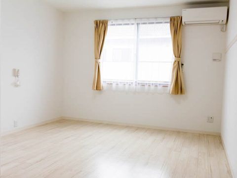 レースカーテンとカーテンが付いた大きな窓があり、エアコンや緊急通報装置を設置した部屋。