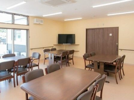 大きなテレビが置かれている食堂にはたくさんの木製のダイニングテーブルが置かれている。