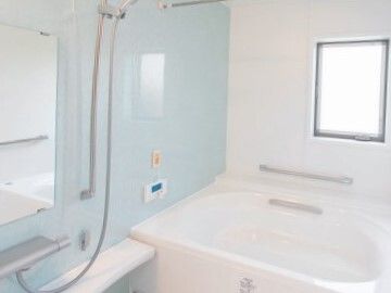 白とライトブルーの浴室内には一人用の浴槽が設置され、シャワーやオレンジの呼び出しボタンもある。