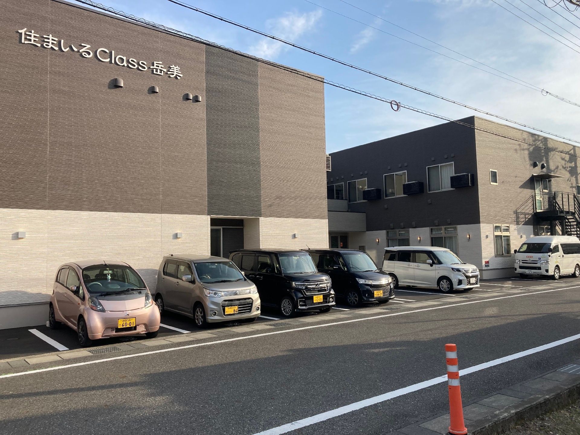 ブラウン系の２階建ての建物は日当たり良好で敷地内には駐車場があり、すっきりとしたデザインの外観。