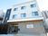 3階建ての建物の1階部分はレンガ調の外壁で2階から上は白とダークグレーの外壁。1階部分には屋根がある。