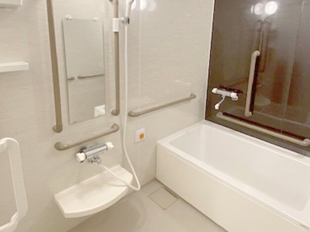 手すりが設置され、一人用の浴槽が設置された浴室にはオレンジの呼び出しボタンも付いている。