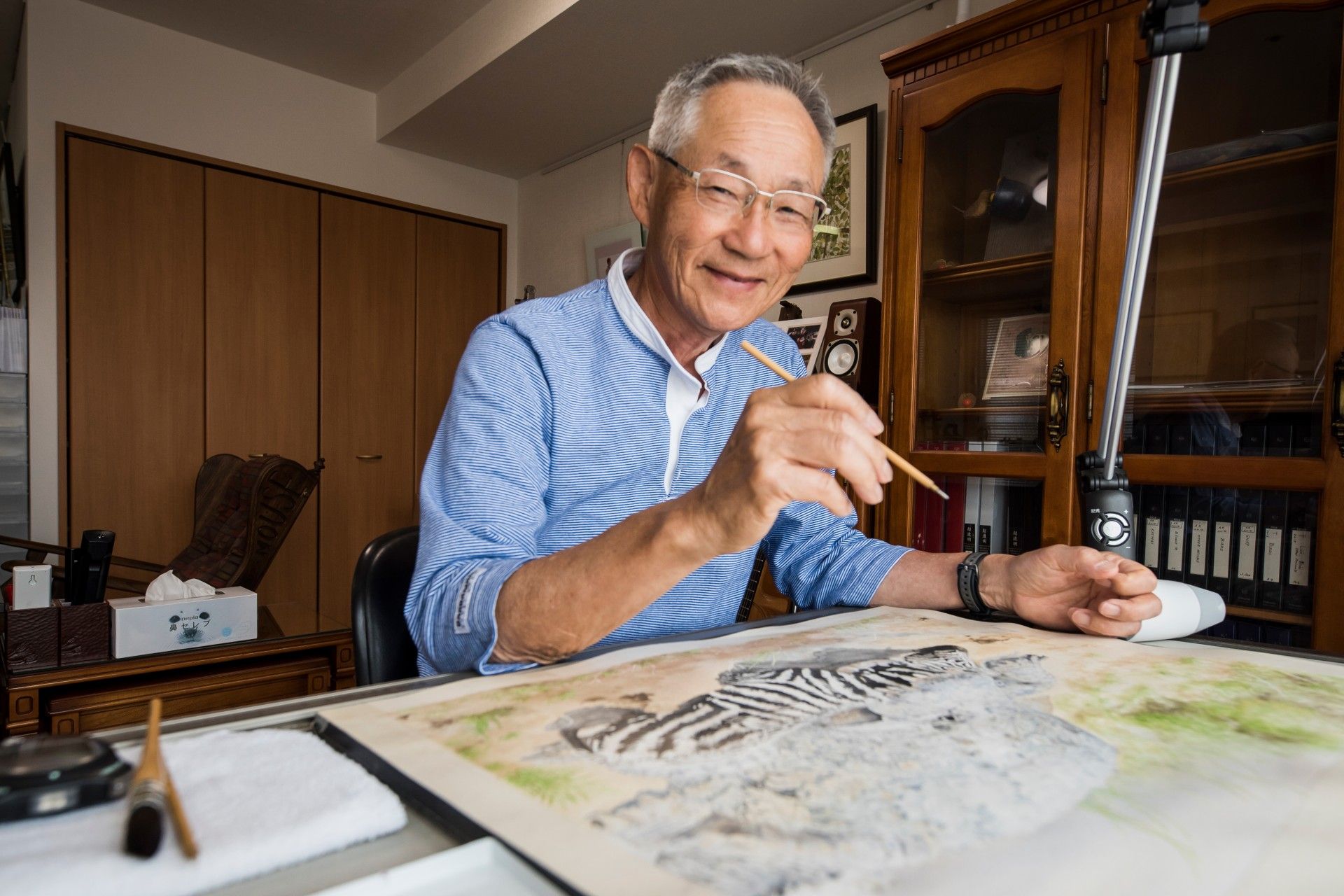 ソファーが配置され、壁には絵画、大きな花瓶には花が活けられたスペース