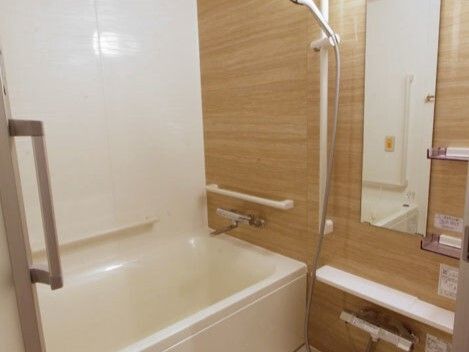 手すりがたくさん付いた一人用の浴槽が設置されている浴室にはシャワーや呼び出しボタンもある。