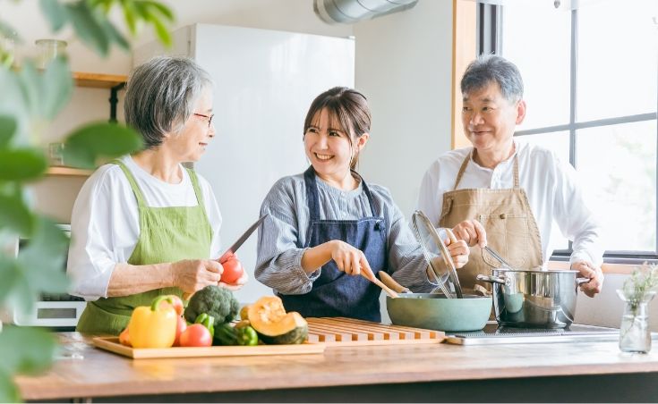 男女３名が微笑みながら料理をしている様子