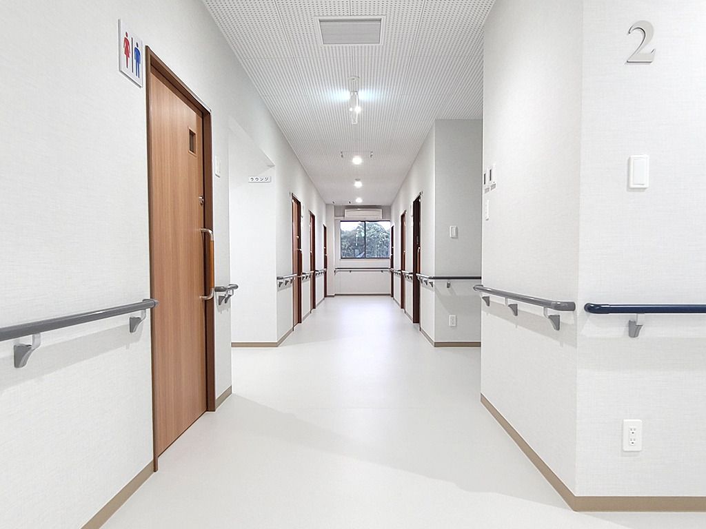 手すりが付いた廊下には物はなく、右手前にはトイレのマークがついたドアもある。