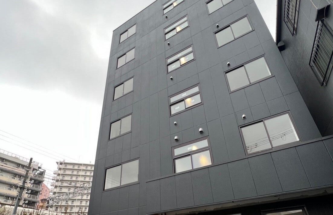 ダークグレーの背の高い建物が建っていて、窓もたくさん付いている。