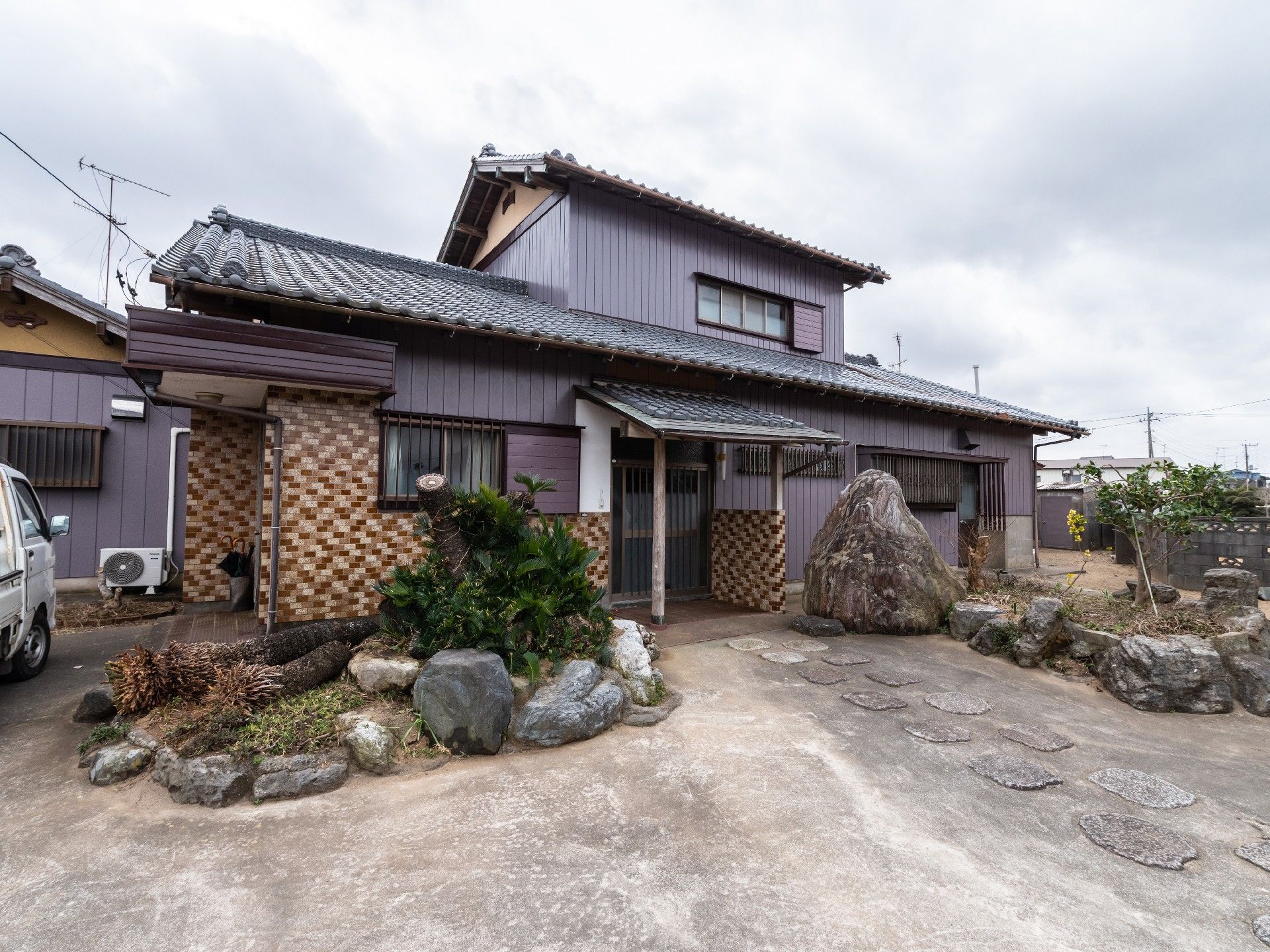 広い庭付きの和風の２階建ての建物。庭には洗濯物干し場もあり、軒下にはベンチなども置かれている。