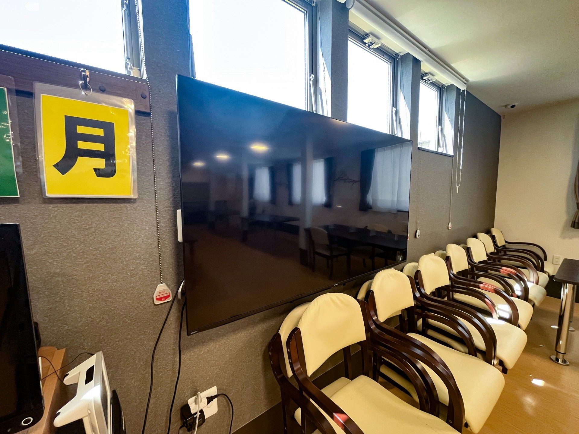 大きなテレビと椅子の並ぶ部屋