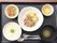 具のない酸いものにおかゆ、刻まれたサラダや肉の炒めた料理などが黒いトレーに並んでいる。
