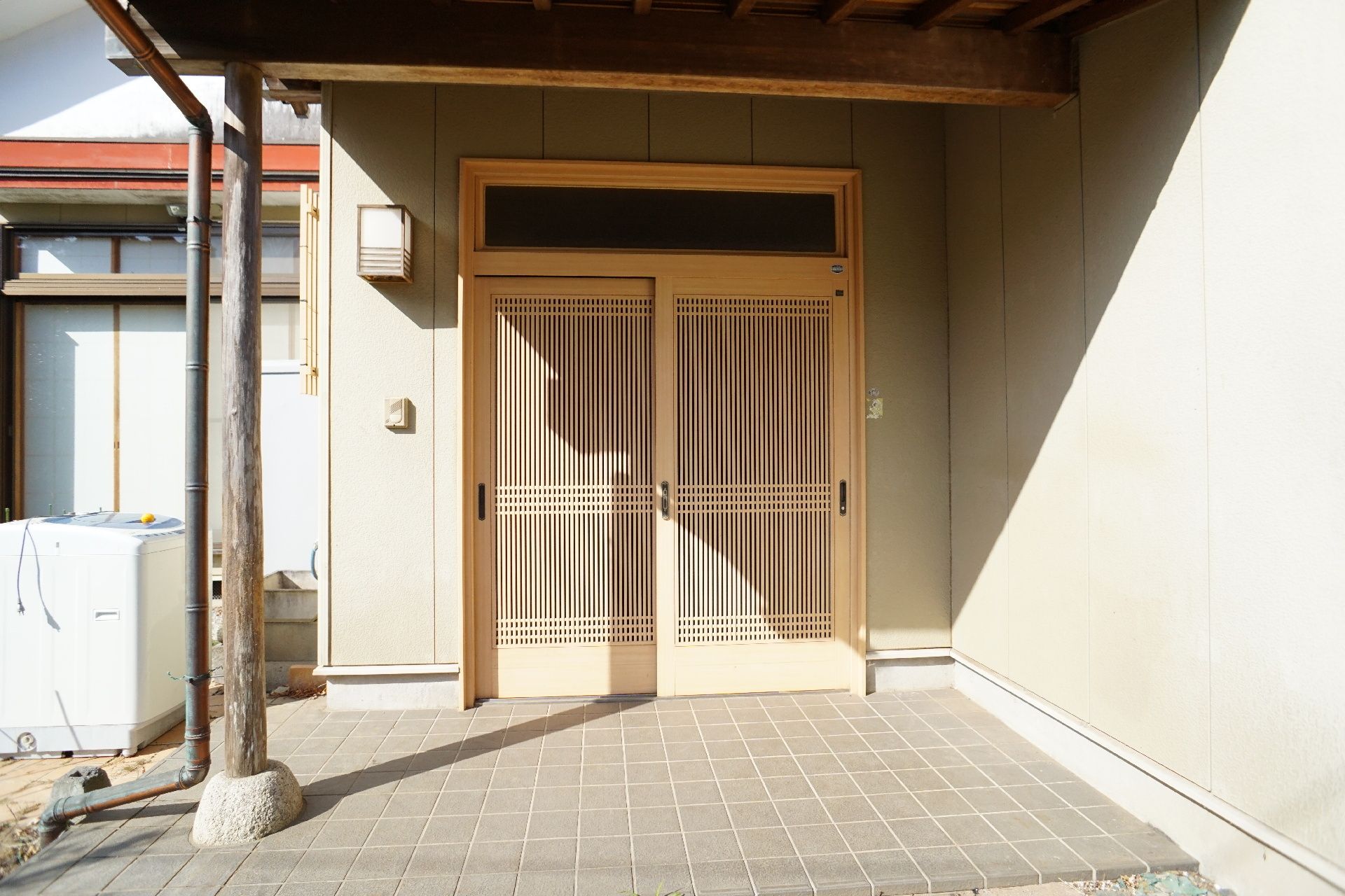 笑顔で車いすに座っている眼鏡をかけた高齢女性と付き添っている白衣を着た女性スタッフ。