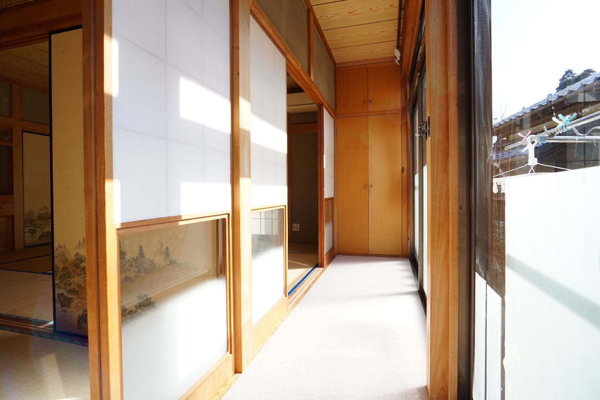 ポロシャツを着た若い女性スタッフと白髪の高齢女性が笑顔で木製のテーブルを囲んでいる。