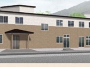 ブラウンと白の２階建ての建物は横に長く、玄関には屋根があり、周辺には自然が多くある。