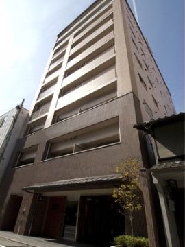 玄関前にグリーンを配置した縦長のツートーンカラーの建物
