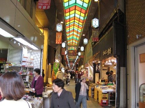商店が並んでおり、大勢の人が買い物を楽しんでいる。アーケードの屋根は、カラフルなステンドグラスである。