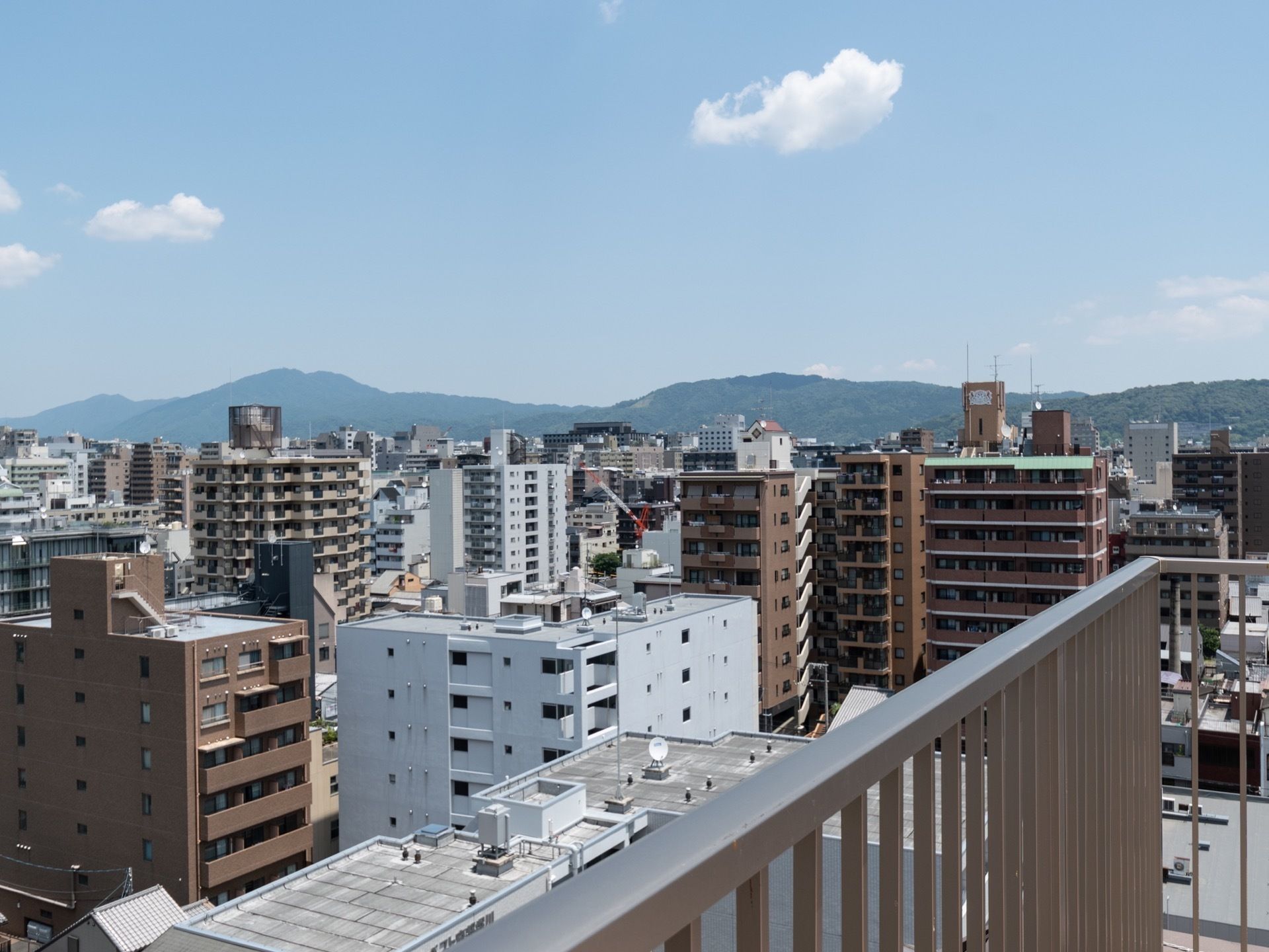 屋上の柵ごしに、街並みと山が見える。周囲には高い建物がないので、遠くまで見渡すことができ、非常に眺めが良い。