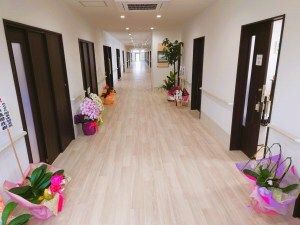 幅の広いまっすぐな廊下は両サイドに手すりが設置され、観葉植物やお祝いの花が飾られている。