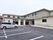 広い駐車場が付いた２階建ての建物の玄関には手すり付きのスロープが設置されている。