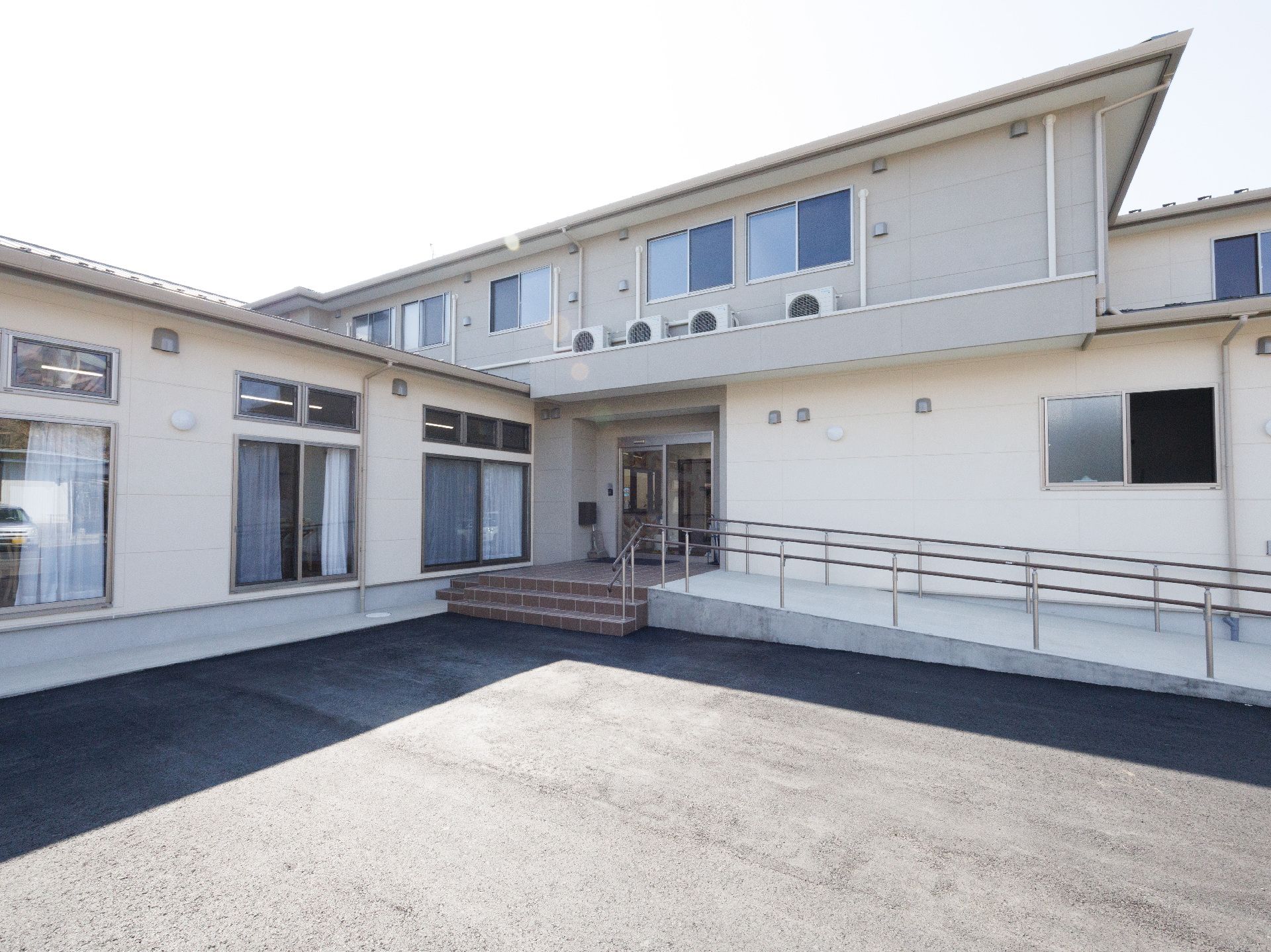 階段とスロープが設置された2階建ての建物