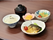 煮魚や白いご飯、汁物、野菜の小鉢などが並べられている木製のダイニングテーブル。