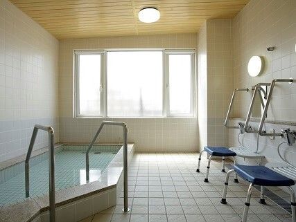 カルテのようなものを見ながら話しているエプロンを付けた若い女性スタッフとカーディガンを着た高齢女性。