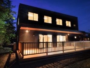 2階建ての建物には明かりが灯り、周辺は日が暮れて暗くなっている。
