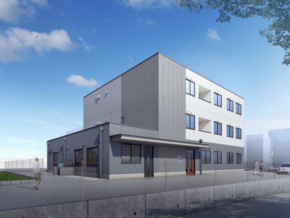 白とライトグレーの建物は3階建てで、駐車場も完備され、たくさんの窓が付いている。