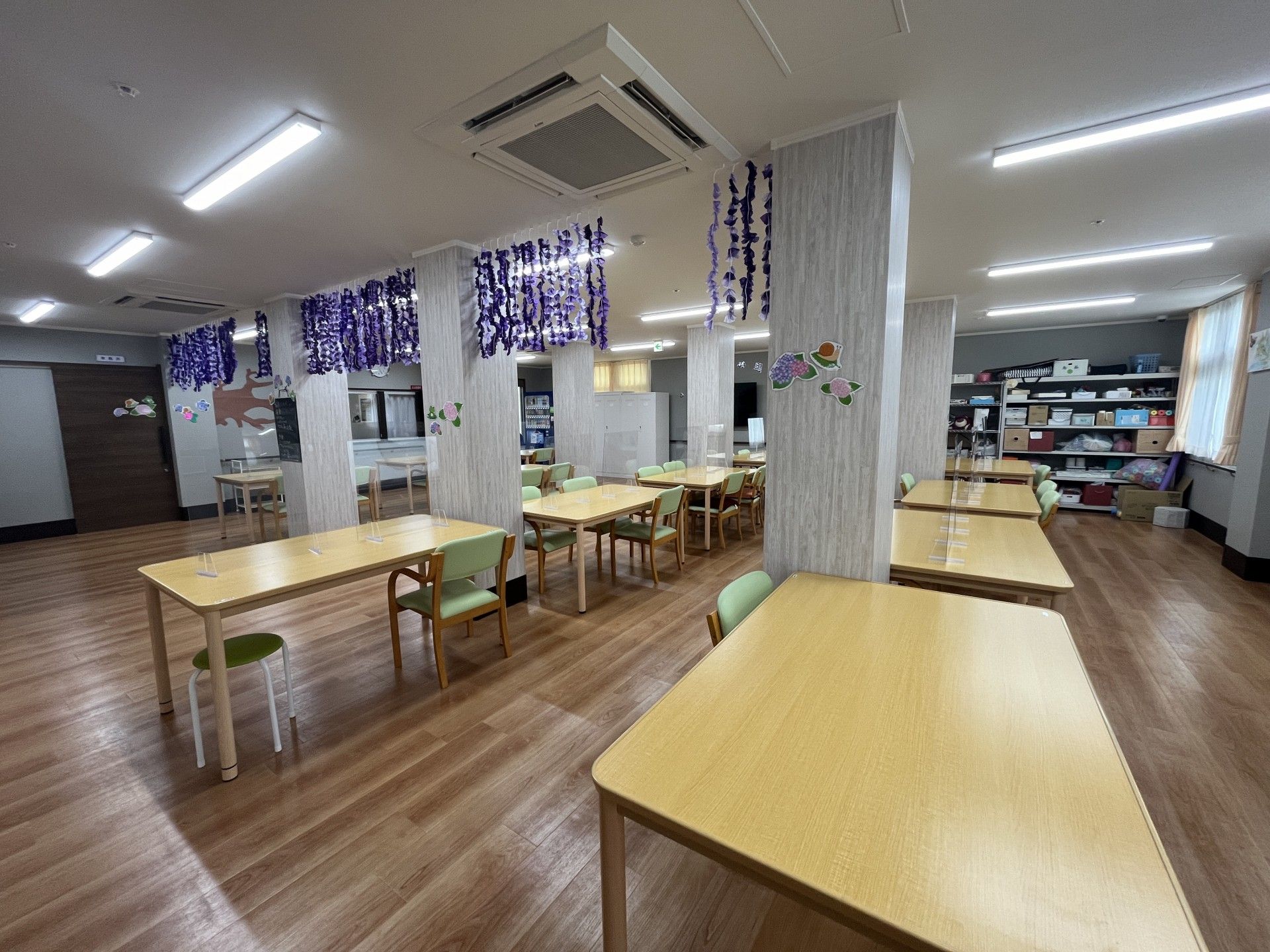 眼鏡をかけた高齢男性が車いすに座り、そばにいる高齢女性と笑顔で話している。