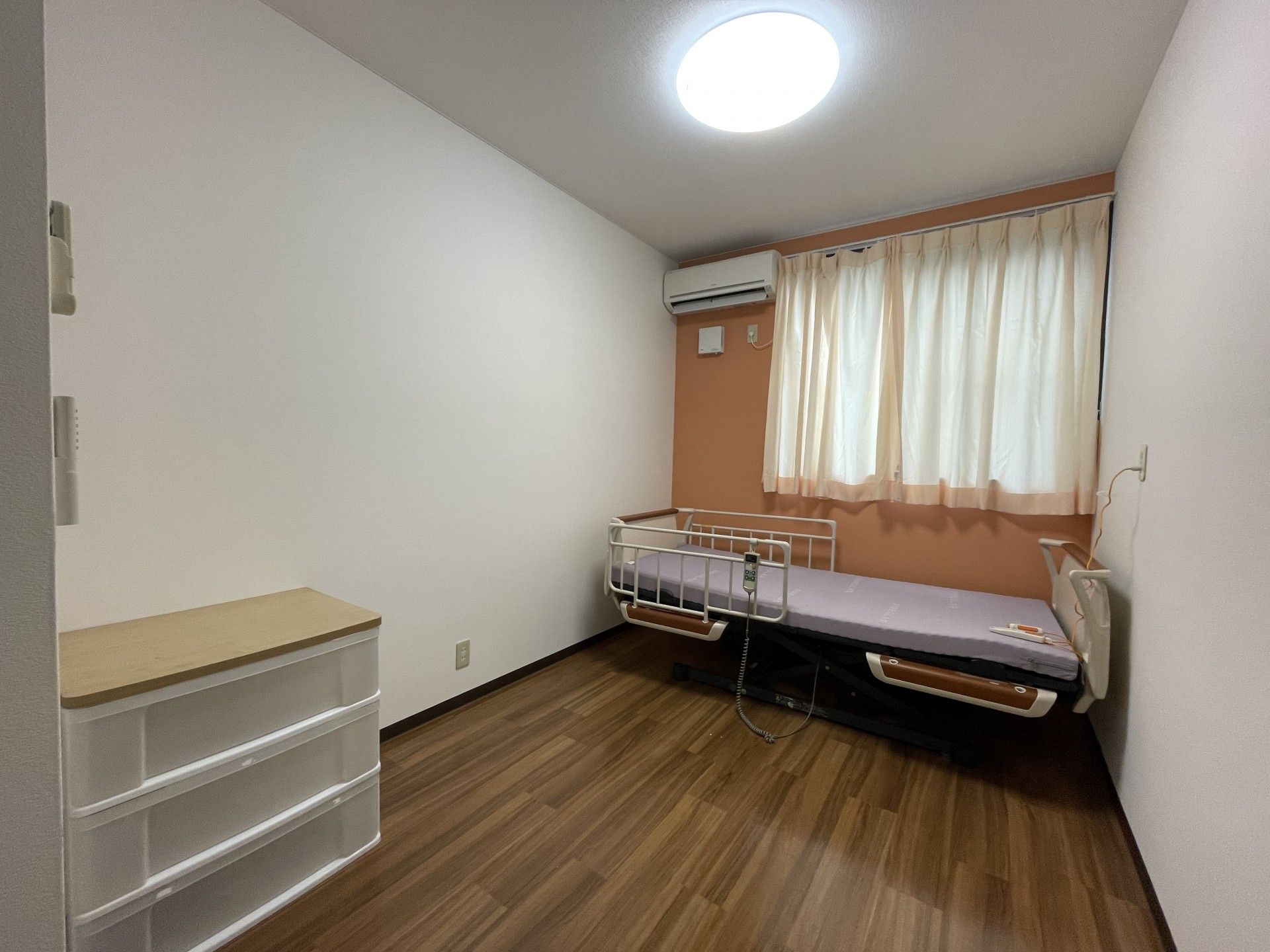 日当たりのいい屋外で笑顔で過ごしている車いすの高齢女性と付き添いのエプロンを付けた女性スタッフ。