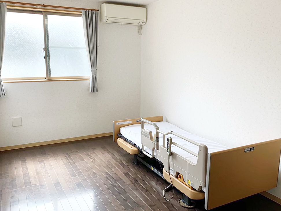 笑顔で並んで立ち、体操をしているブルーのユニフォームを着た男性スタッフと高齢女性。