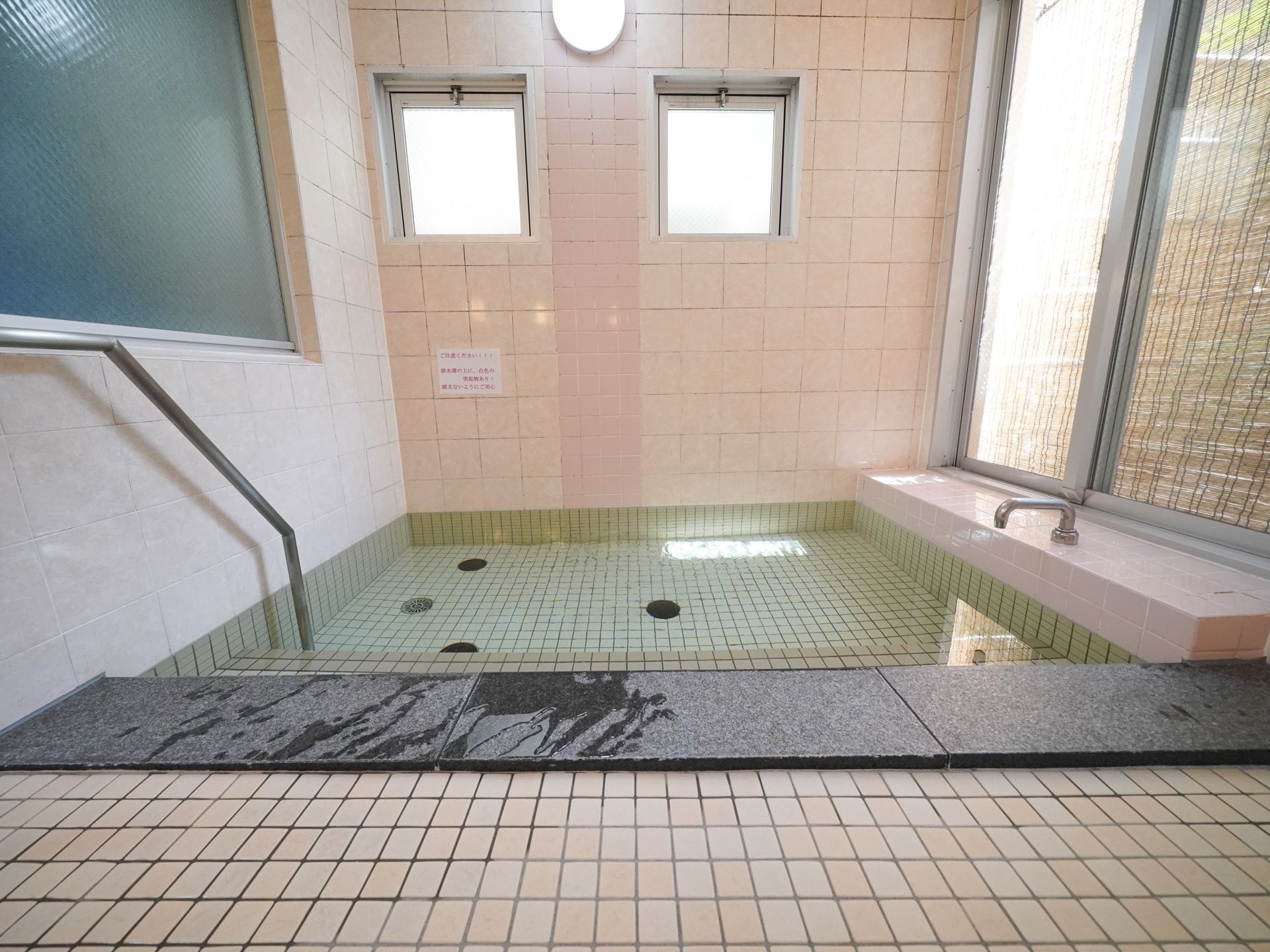 浴槽の左側の壁には金属製でしっかりとした手すりが設置されており、入居者様はそれを伝いながら安全に入浴することができる。