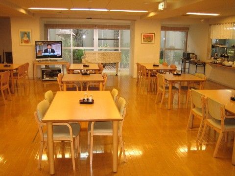 広々としたスペースに4人掛けのテーブルと椅子が並べられている。厨房が隣接し、ウッドデッキにアクセスできる。